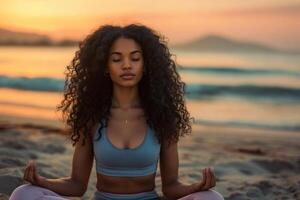 un' giovane nero donna con lungo Riccio capelli fare yoga su il spiaggia foto