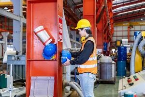 asiatico lavoratore è sospeso il suo sicurezza casco su il cremagliera dentro il pesante industriale fabbrica per protezione e incidente prevenzione concetto foto