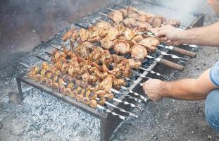 uomo che cucina carne barbecue all'aperto. foto