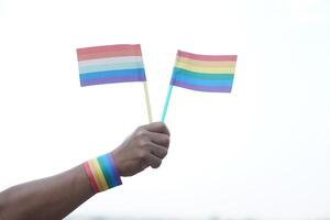 vicino su mano detiene arcobaleno colori bandiere. concetto, LGBTQ celebrazione nel orgoglio mese, giugno. simbolo di lgbt Comunità in giro il world.support umano giusto di Genere diversità. foto