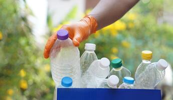 mano detiene Usato plastica bottiglia per mettere nel Rifiuto bidone per raccolta differenziata. concetto, ordinamento spazzatura campagna prima gettare lontano per riutilizzo o riciclare. ambiente conservazione. eco amichevole attività. foto