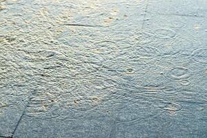 spruzzi di acqua e gocce di pioggia su pavimentazione lastre. piovoso tempo metereologico concetto. foto