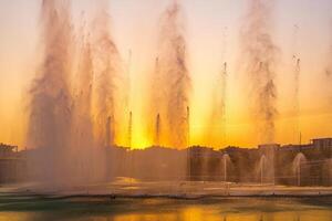 grande fontane su il artificiale stagno, illuminato di luce del sole a tramonto nel compito città parco a estate. foto