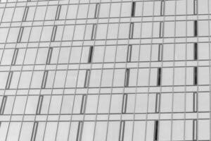 frammento di un' moderno ufficio costruzione. astratto geometrico sfondo. parte di il facciata di un' grattacielo con bicchiere finestre. nero e bianca. foto