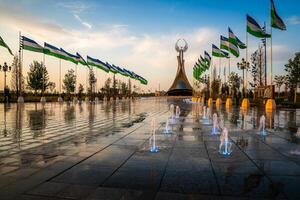 Uzbekistan, compito - Maggio 5, 2023 fontane nel un' sfondo di monumento di indipendenza nel il modulo di un' stele con un' humo uccello e agitando bandiere su un' tramonto dopo pioggia nel il nuovo Uzbekistan parco. foto