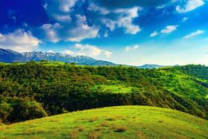 colline e montagne coperto con giovane verde erba e illuminato di il sole su un' soleggiato giorno. foto