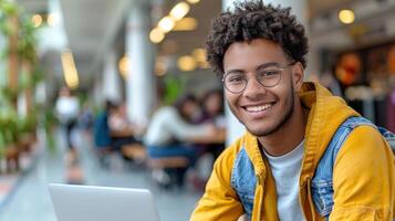 un' uomo indossare occhiali, un' giallo giacca, sorrisi mentre Lavorando su un' il computer portatile foto