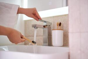 Da donna mani sotto in esecuzione acqua nel il bagno. mattina routine. foto