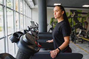 attraente giovane gli sport donna è Lavorando su nel palestra. fare cardio formazione su tapis roulant. in esecuzione su routine foto