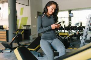 bellissima giovane donna sms e sociale networking mentre nel un' palestra. foto