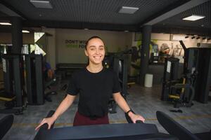 donna treni su un' routine nel il palestra. giovane fitness ragazza in esecuzione su routine macchina. gli sport esercizi per peso perdita foto