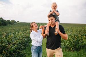 contento famiglia con poco figlia la spesa tempo insieme nel soleggiato campo. foto