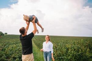 contento famiglia con poco figlia la spesa tempo insieme nel soleggiato campo. foto