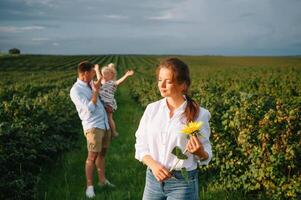 contento famiglia con poco figlia la spesa tempo insieme nel soleggiato campo. foto