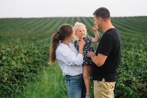 contento famiglia con poco figlia la spesa tempo insieme nel soleggiato campo. foto