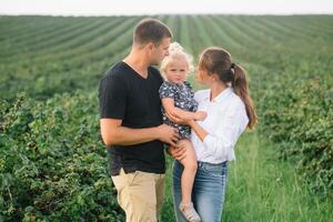 contento famiglia con poco figlia la spesa tempo insieme nel soleggiato campo foto