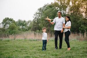 padre, madre e figlio giocando con giocattolo aereo nel il parco. amichevole famiglia. persone avendo divertimento all'aperto. immagine fatto su il sfondo di il parco e blu cielo. concetto di un' contento famiglia foto