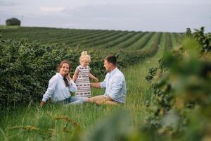 contento famiglia a piedi nel il parco. mamma, papà e figlia camminare all'aperto, genitori Tenere il bambino ragazze mani. infanzia, genitorialità, famiglia obbligazioni, matrimonio concetto. foto