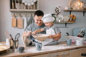 giovane uomo e il suo figlio con forno foglio nel cucina. padre con poco figlio su il cucina. foto