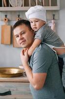 giovane uomo e il suo figlio con forno foglio nel cucina. padre con poco figlio su il cucina foto