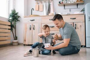 giovane uomo e il suo figlio con forno foglio nel cucina. padre con poco figlio su il cucina. foto