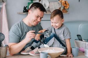giovane uomo e il suo figlio con forno foglio nel cucina. padre con poco figlio su il cucina foto