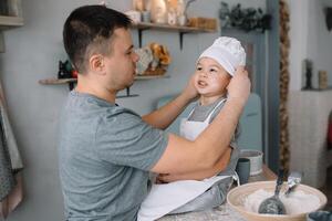 giovane uomo e il suo figlio con forno foglio nel cucina. padre con poco figlio su il cucina. foto