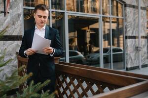 giovane attività commerciale uomo con documenti e mobile Telefono vicino di moderno costruzione. foto