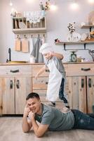 giovane uomo e il suo figlio con forno foglio nel cucina. padre con poco figlio su il cucina. foto