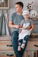 giovane uomo e il suo figlio con forno foglio nel cucina. padre con poco figlio su il cucina foto