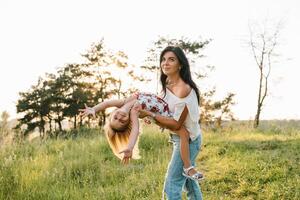 elegante madre e bello figlia avendo divertimento su il natura. contento famiglia concetto. bellezza natura scena con famiglia all'aperto stile di vita. famiglia riposo insieme. felicità nel famiglia vita. madri giorno. foto