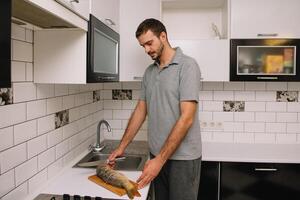 uomo taglio fresco pesce nel cucina nel casa. uomo macellazione pesce per cucinare. foto