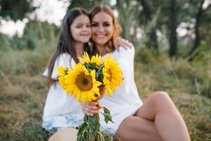 elegante madre e bello figlia avendo divertimento su il natura. contento famiglia concetto. bellezza natura scena con famiglia all'aperto stile di vita. famiglia riposo insieme. felicità nel famiglia vita. madri giorno. foto