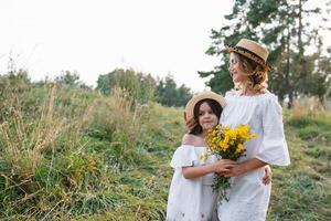 elegante madre e bello figlia avendo divertimento su il natura. contento famiglia concetto. bellezza natura scena con famiglia all'aperto stile di vita. famiglia riposo insieme. felicità nel famiglia vita. madri giorno. foto