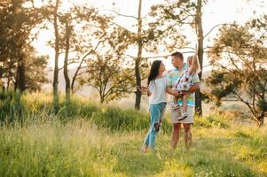 contento famiglia di tre persone a piedi il erba nel il parco foto