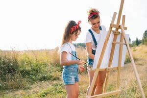 famiglia, bambini e persone concetto - contento madre e figlia disegno e parlando al di sopra di verde sfondo. La madre di giorno. foto