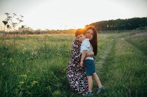 elegante madre e bello figlio avendo divertimento su il natura. contento famiglia concetto. bellezza natura scena con famiglia all'aperto stile di vita. contento famiglia riposo insieme. felicità nel famiglia vita. madri giorno foto