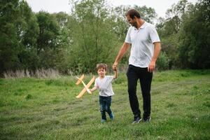 padre e figlio giocando nel aviatore. superuomo papà e figlio avendo divertimento. immaginazione e sogni di essere un' pilota. bambino pilota con aereo su papà Indietro. viaggio e vacanza nel estate. libertà. foto