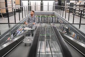 un' uomo con un' shopping carrello su un scala mobile nel un' hardware negozio. foto