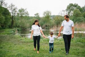 contento famiglia madre padre e bambino figlio su natura su tramonto. mamma, papà e ragazzo ridendo e abbracciare, godendo natura fuori. soleggiato giorno, bene umore. concetto di un' contento famiglia foto