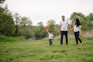 padre, madre e figlio giocando con giocattolo aereo nel il parco. amichevole famiglia. persone avendo divertimento all'aperto. immagine fatto su il sfondo di il parco e blu cielo. concetto di un' contento famiglia foto