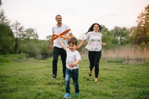 padre, madre e figlio giocando con giocattolo aereo nel il parco. amichevole famiglia. persone avendo divertimento all'aperto. immagine fatto su il sfondo di il parco e blu cielo. concetto di un' contento famiglia. foto