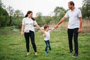 contento famiglia madre padre e bambino figlio su natura su tramonto. mamma, papà e ragazzo ridendo e abbracciare, godendo natura fuori. soleggiato giorno, bene umore. concetto di un' contento famiglia foto