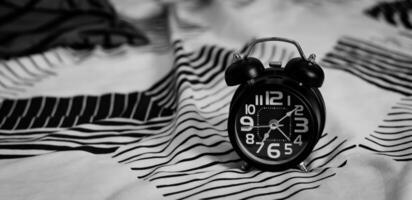 Scadenza e tempo gestione concetto. nero retrò allarme orologio su letto. tempo per scia su per il mattina routine foto