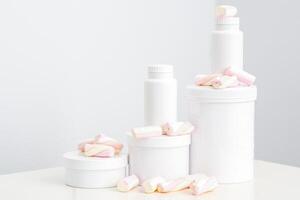 cosmetico cura della pelle confezione. bellezza Prodotto su bianca sfondo. bianca barattoli con marshmallows su il bianca tavolo. foto