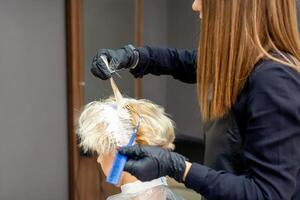 colorazione femmina capelli nel il capelli salone. giovane donna avendo sua capelli tinti di estetista a il bellezza salotto. foto