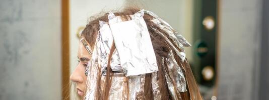 capelli sventato durante capelli tintura di un' giovane donna nel capelli salone vicino su. foto