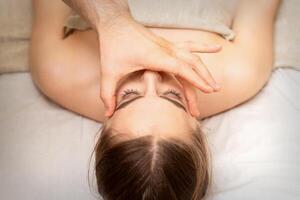 viso massaggio con dita di un' massaggiatore. femmina facciale pelle cura a un' bellezza terme salone. foto