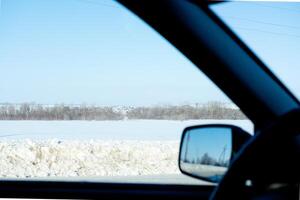 Visualizza a partire dal il auto finestra su il nevoso strada. inverno viaggio su settentrionale strade foto