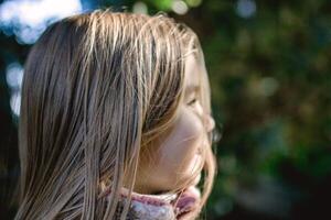 ritratto di un' giovane ragazza con lungo biondo capelli sorridente all'aperto nel un' naturale ambientazione. foto